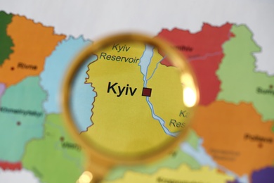 Golden magnifying glass above Kyiv region on map of Ukraine, closeup