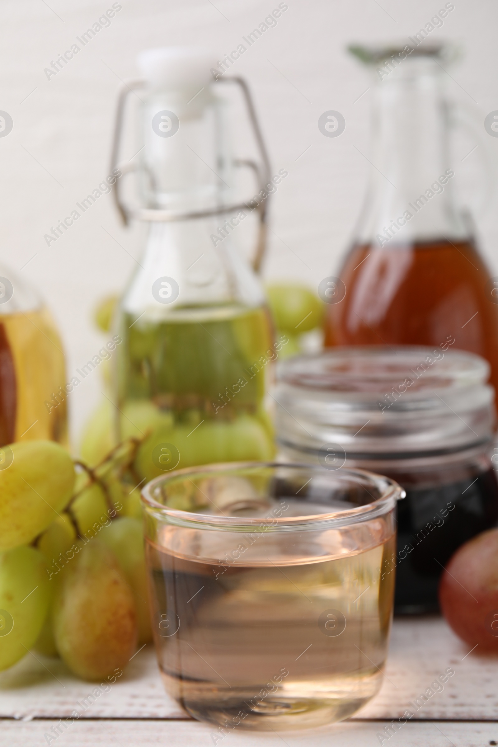 Photo of Different types of vinegar and grapes on wooden table, closeup