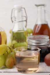 Photo of Different types of vinegar and grapes on wooden table, closeup