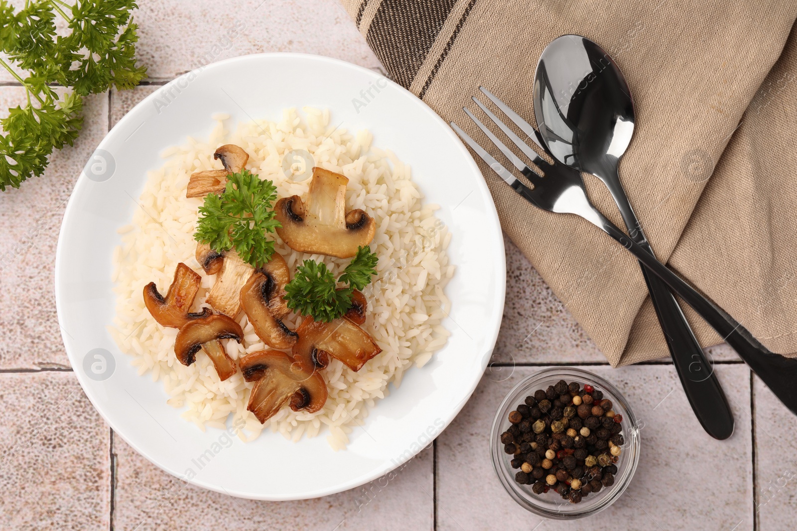 Photo of Delicious rice with parsley and mushrooms served on tiled table, flat lay
