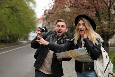 Photo of Couple of tourists with map and camera on city street