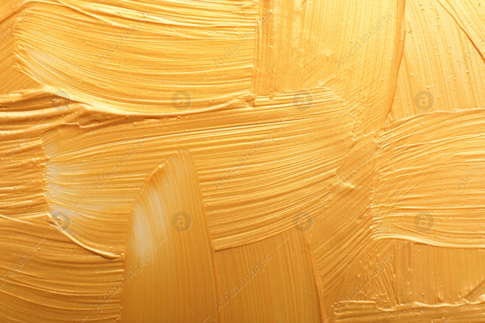 Photo of Strokes of gold paint as background, top view