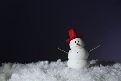 Photo of Funny snowman on snow against dark background, space for text