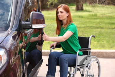 Woman in wheelchair opening door of her van outdoors