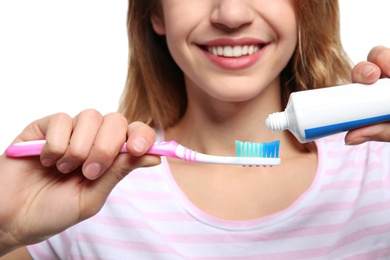 Photo of Young woman with toothbrush and paste on white background, closeup