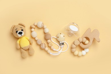Photo of Flat lay composition with pacifier and other baby stuff on beige background