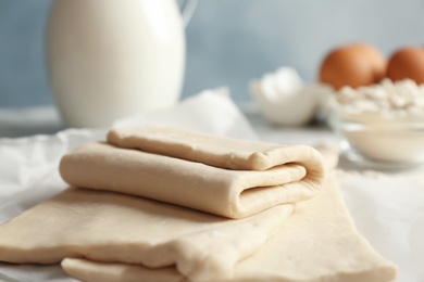 Photo of Fresh raw dough on parchment paper, closeup