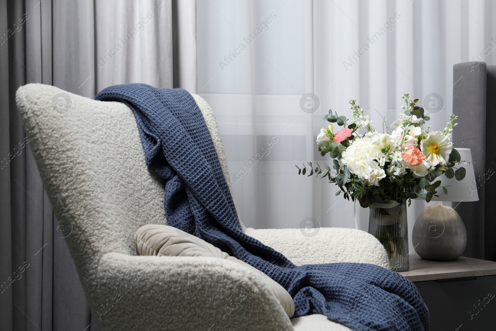 Photo of Bouquet of beautiful flowers near armchair indoors