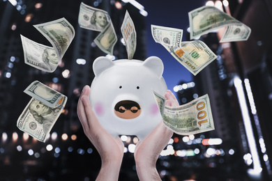 Woman holding piggy bank and American dollars falling outdoors, closeup 