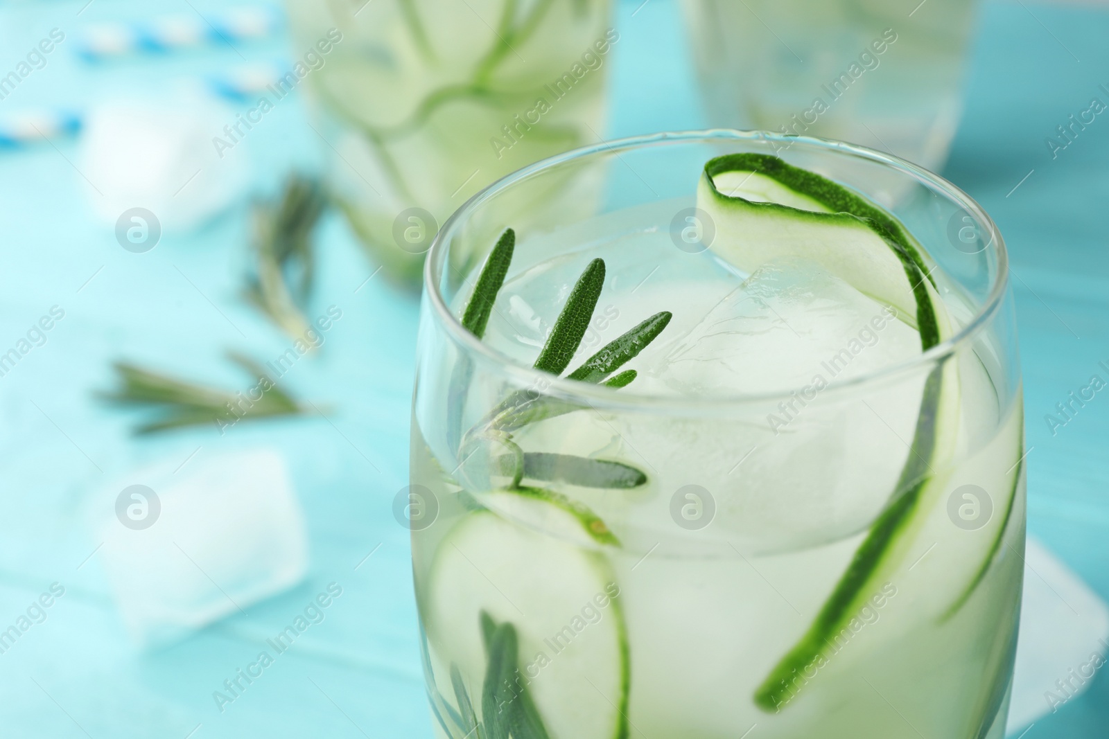 Photo of Glass of refreshing cucumber lemonade on light blue table, closeup and space for text. Summer drink