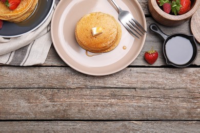 Photo of Tasty pancakes served with butter, honey and berries on wooden table, flat lay. Space for text
