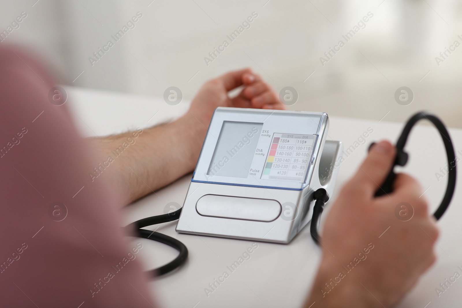 Photo of Man checking blood pressure at table indoors, closeup