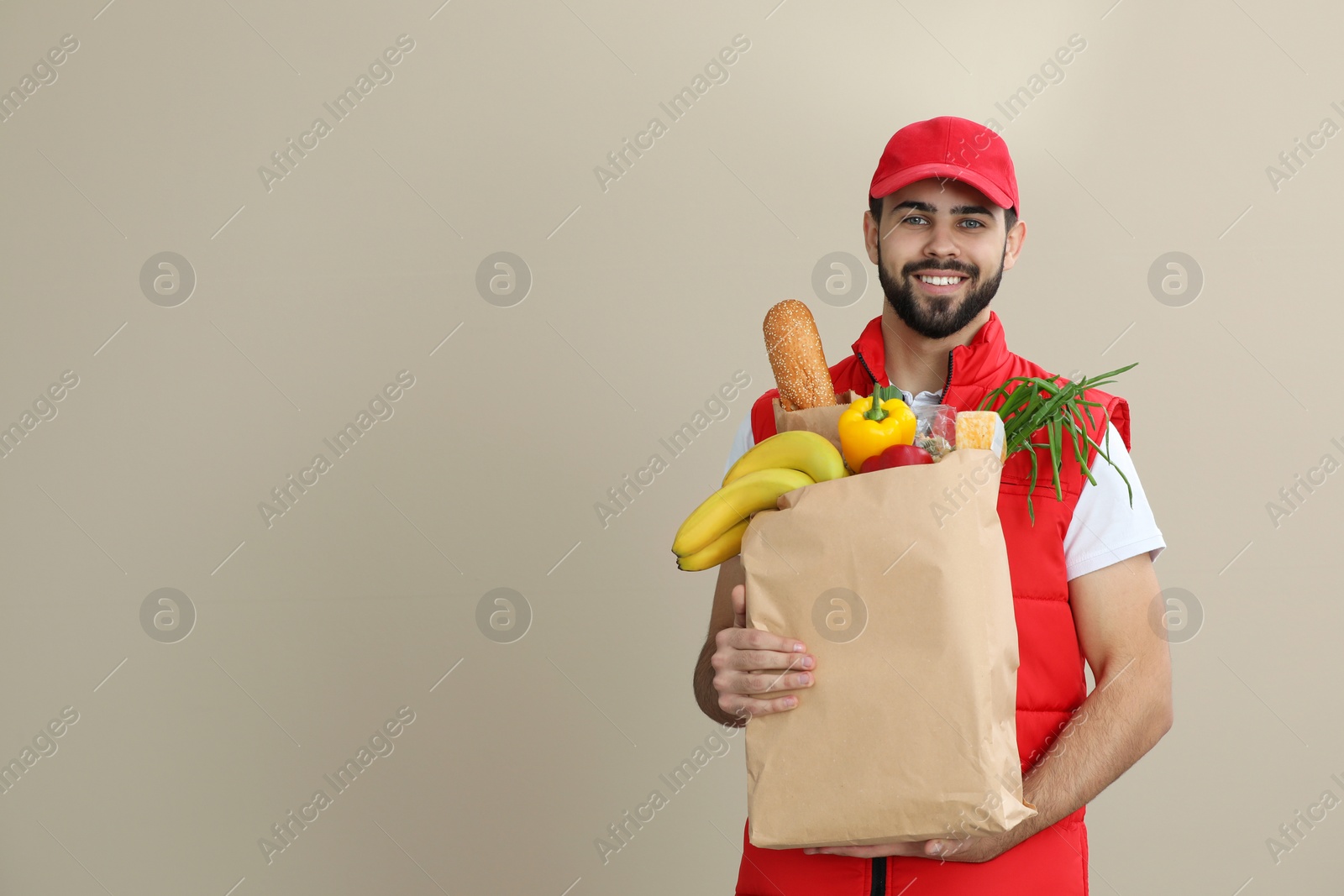 Photo of Man holding paper bag with fresh products on color background, space for text. Food delivery service