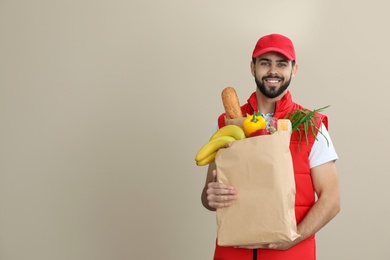 Photo of Man holding paper bag with fresh products on color background, space for text. Food delivery service