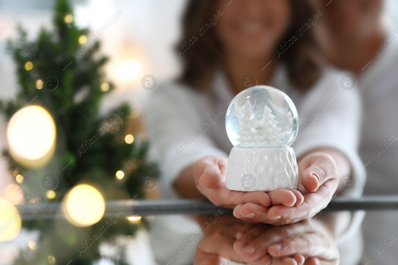 Photo of Happy couple celebrating Christmas, focus on hands with snow globe