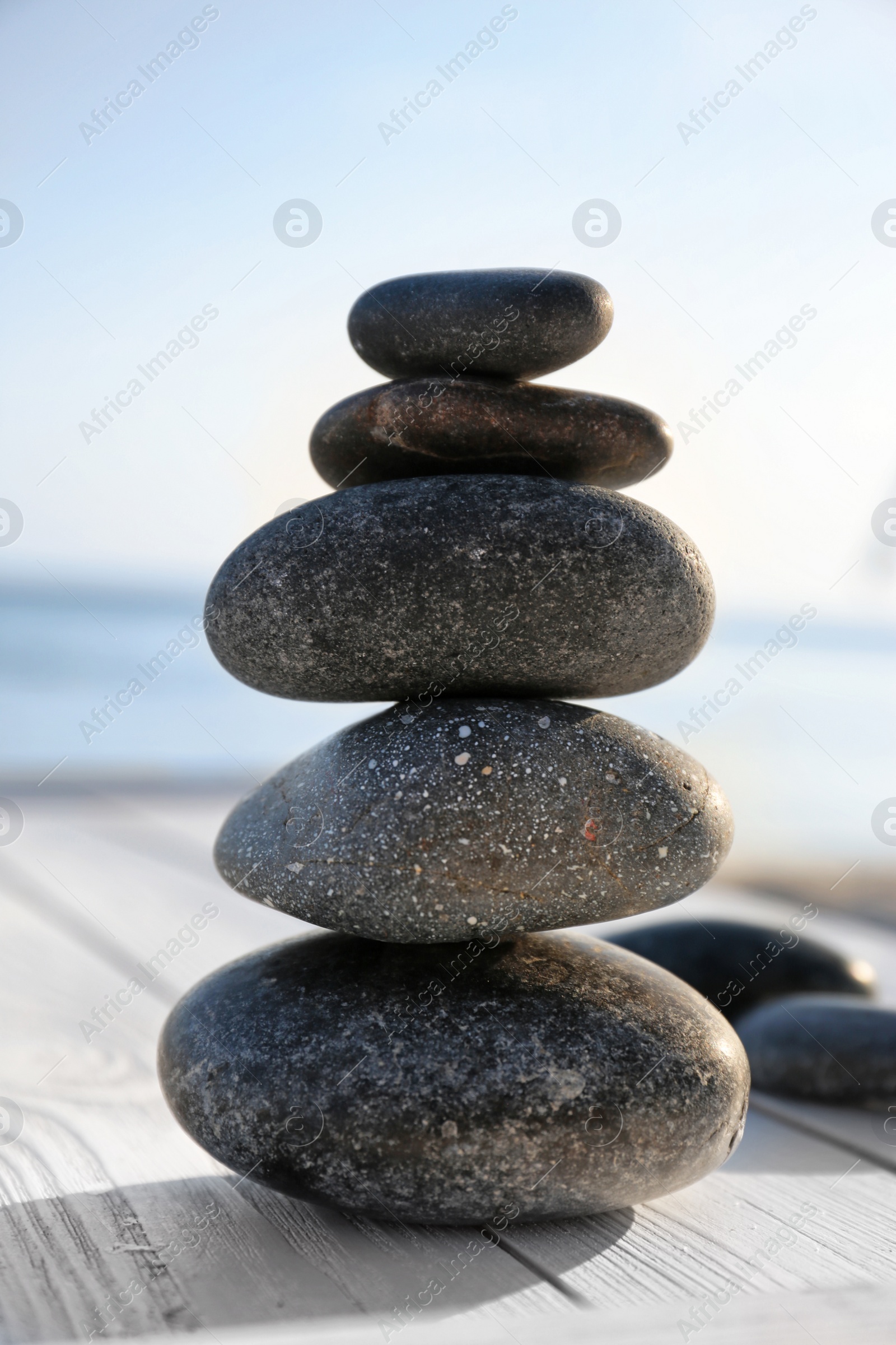 Photo of Stack of stones on wooden deck outdoors. Zen concept