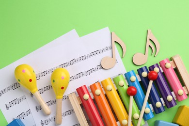 Tools for creating baby songs. Flat lay composition with maracas and xylophone on green background