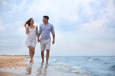 Happy couple having romantic walk on beach. Space for text