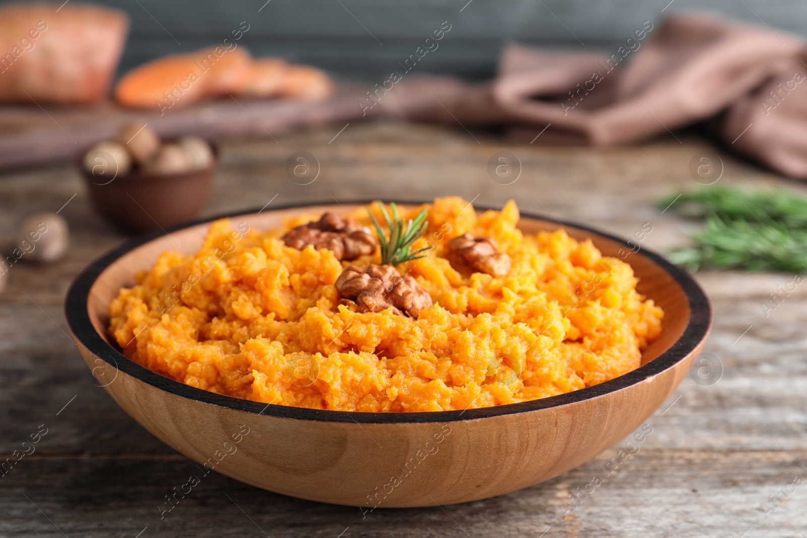 Photo of Bowl with mashed sweet potatoes on wooden table