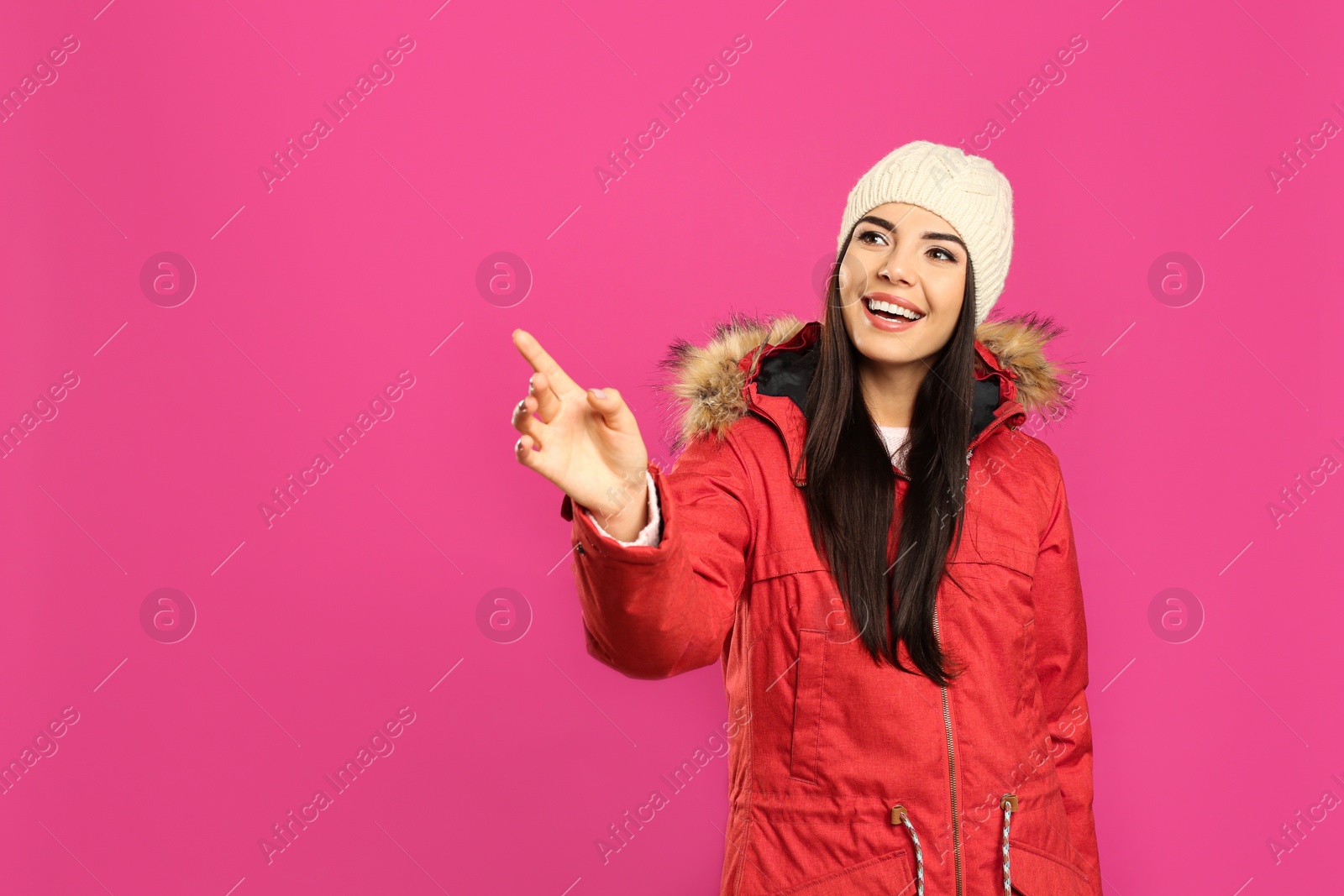 Photo of Happy young woman in warm clothes on pink background, space for text. Winter vacation