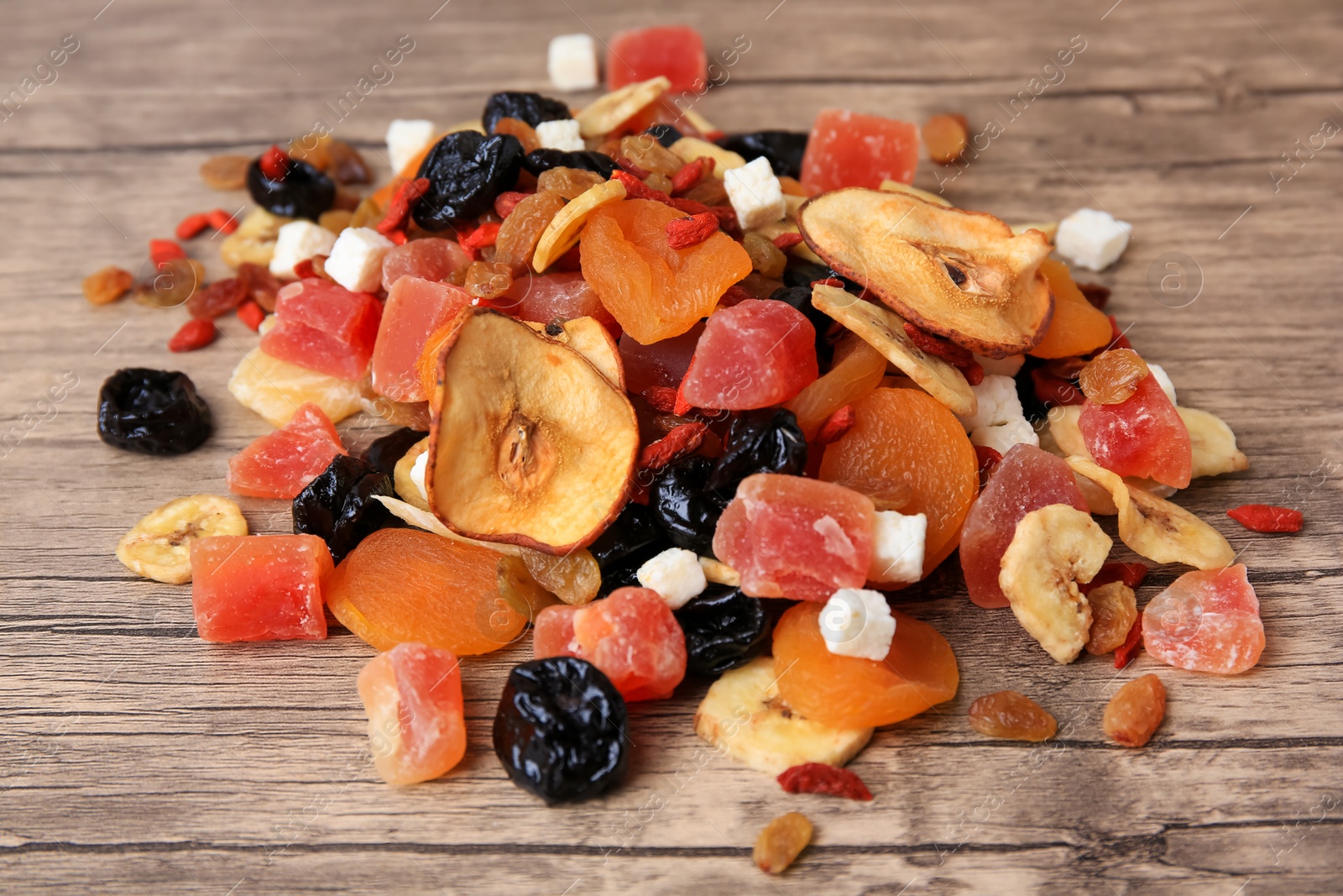 Photo of Pile of different tasty dried fruits on wooden table, closeup