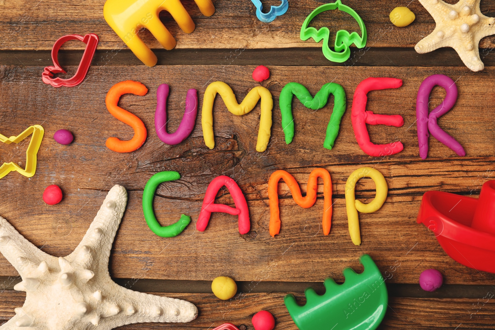 Photo of Text SUMMER CAMP made with play dough on wooden background, top view