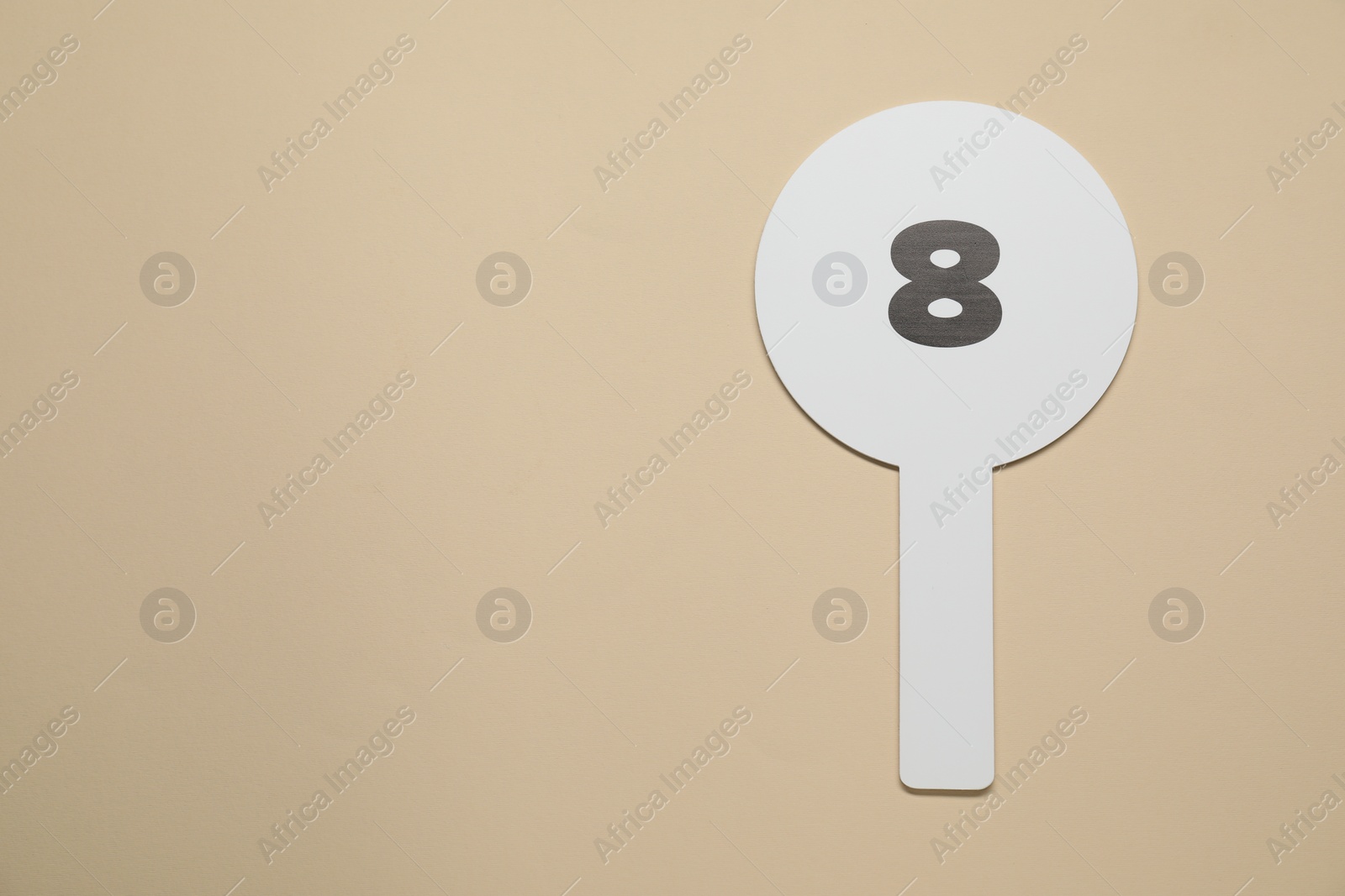 Photo of Auction paddle with number 8 on beige background, top view. Space for text