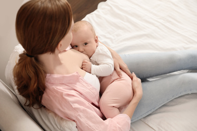 Young woman breast feeding her little baby on bed, above view