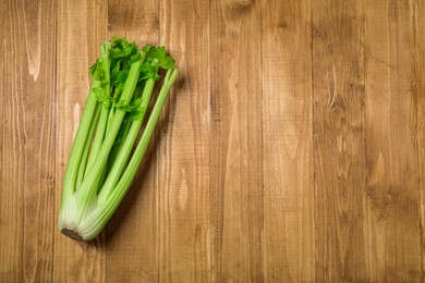Bunch of fresh green celery on wooden table, top view. Space for text