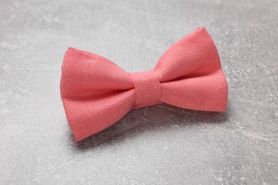 Stylish coral bow tie on light grey background