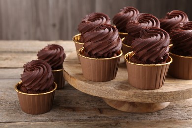 Photo of Delicious chocolate cupcakes on wooden table. Sweet desserts