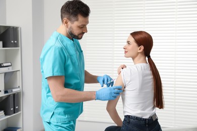 Doctor giving hepatitis vaccine to patient in clinic