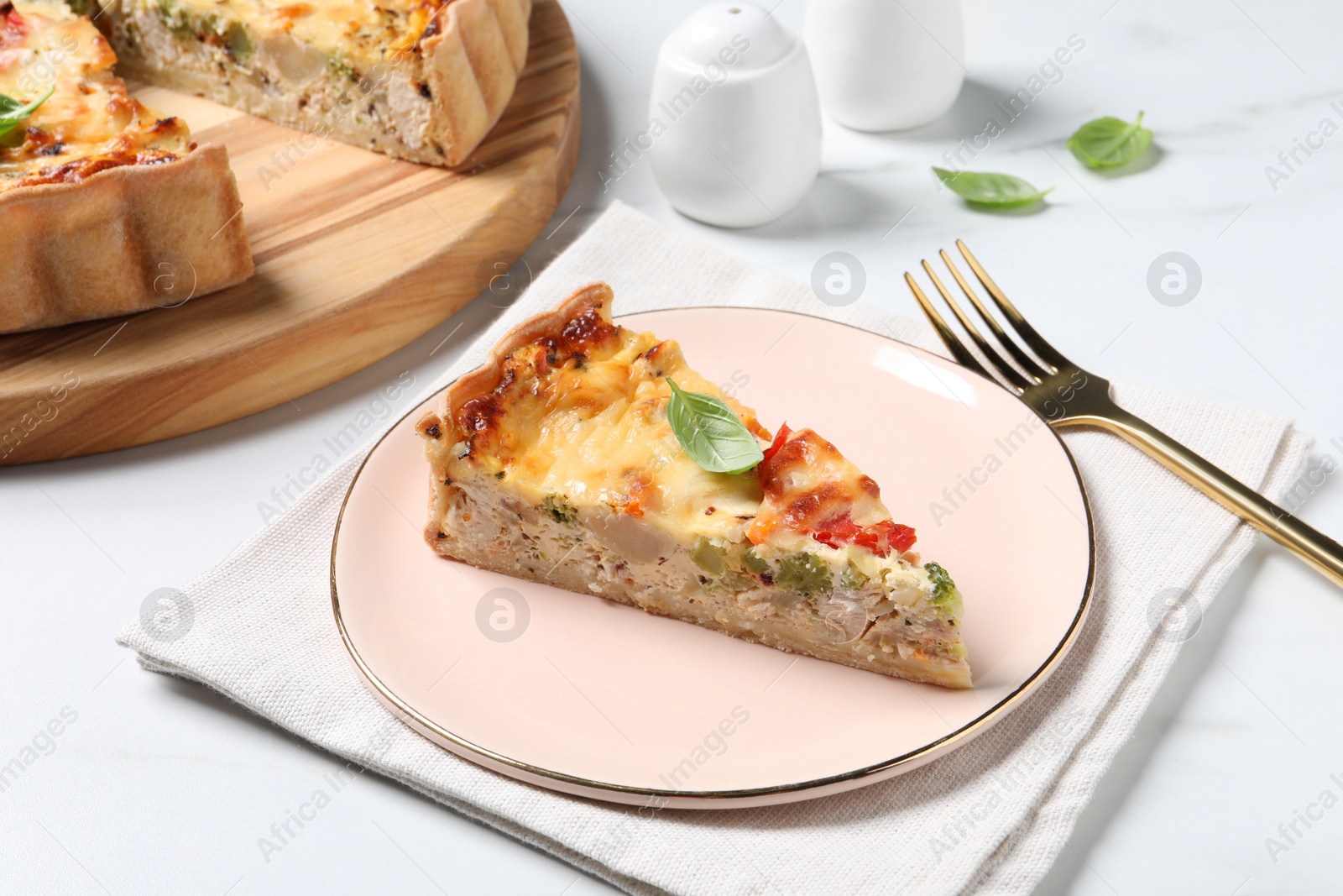 Photo of Tasty quiche with tomatoes, cheese and basil served on white marble table, closeup