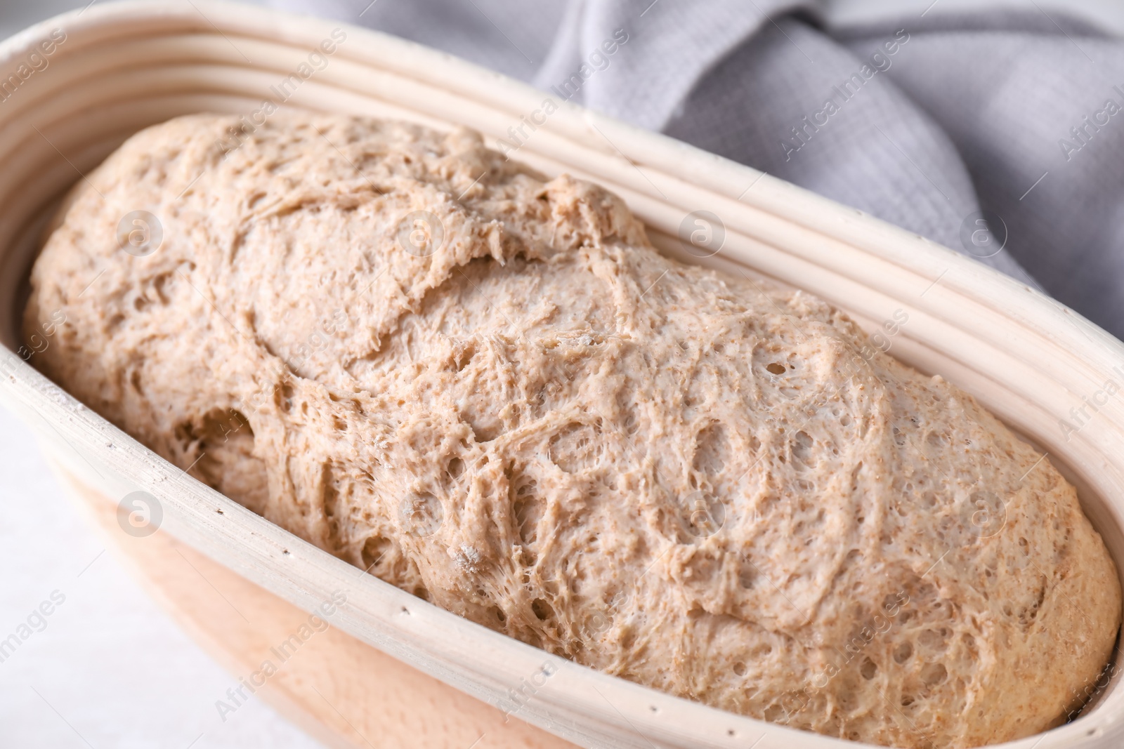 Photo of Fresh sourdough in proofing basket on light table, closeup