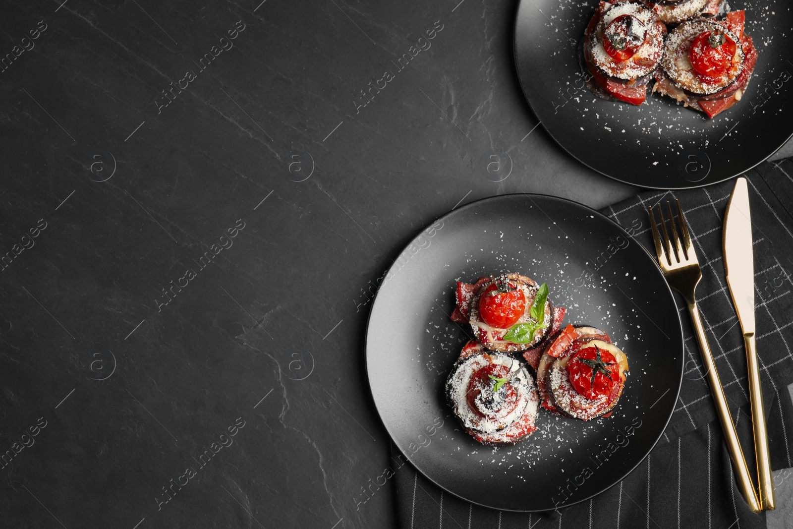 Photo of Baked eggplant with tomatoes, cheese and basil served on black table, flat lay. Space for text