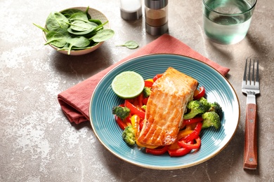 Plate with tasty cooked salmon and vegetables on table