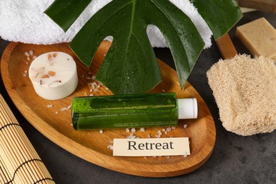 Photo of Card with word Retreat, different spa products and green palm leaf on textured table