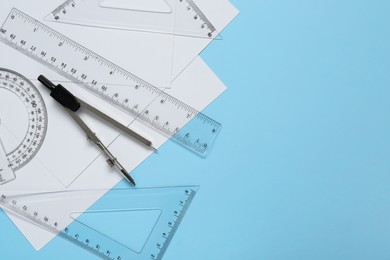 Flat lay composition with different rulers and compass on light blue background. Space for text