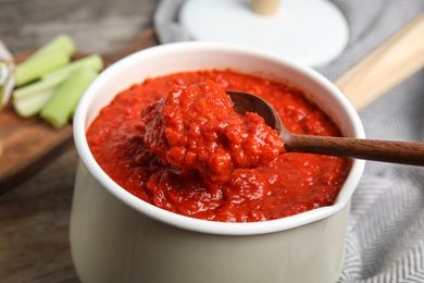 Photo of Spoon and pan with delicious tomato sauce, closeup view