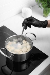 Photo of Woman cooking delicious dumplings in kitchen, closeup