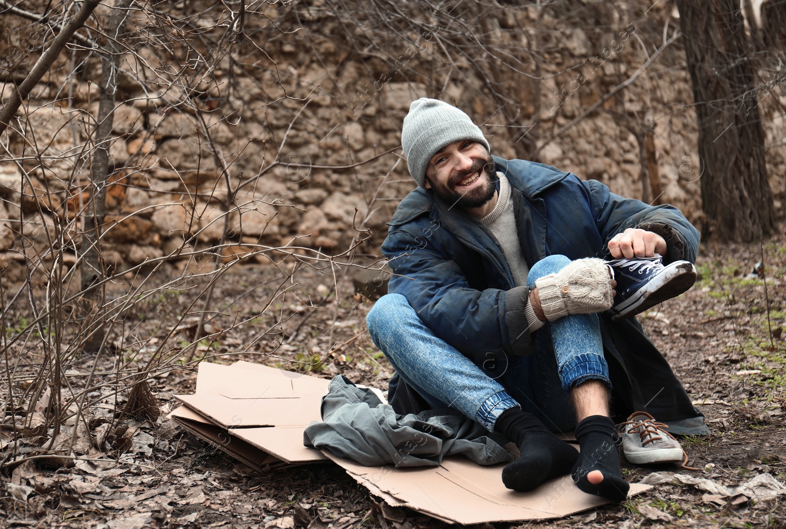 Photo of Poor homeless man sitting on cardboard in city park