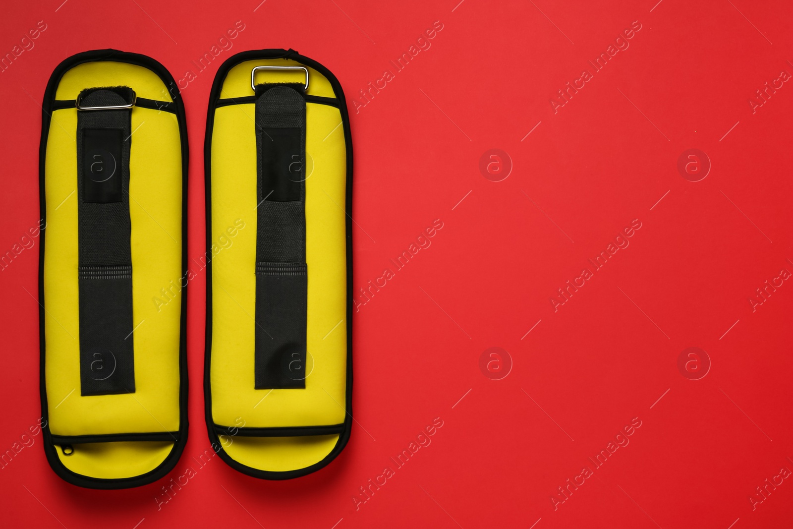 Photo of Yellow weighting agents on red background, flat lay. Space for text
