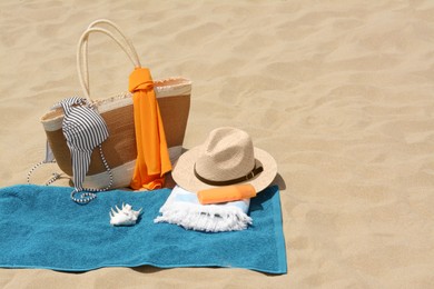 Photo of Blue towel, bag and accessories on sandy beach, space for text