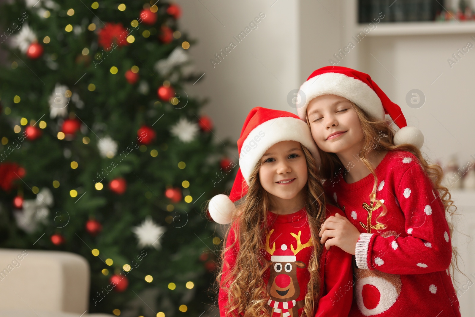 Photo of Cute little girls near Christmas tree at home. Space for text