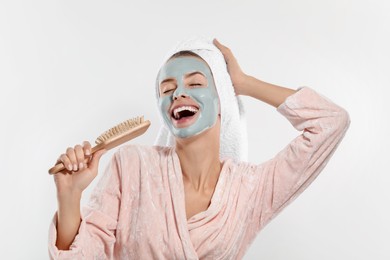 Photo of Woman with face mask and brush singing on white background. Spa treatments