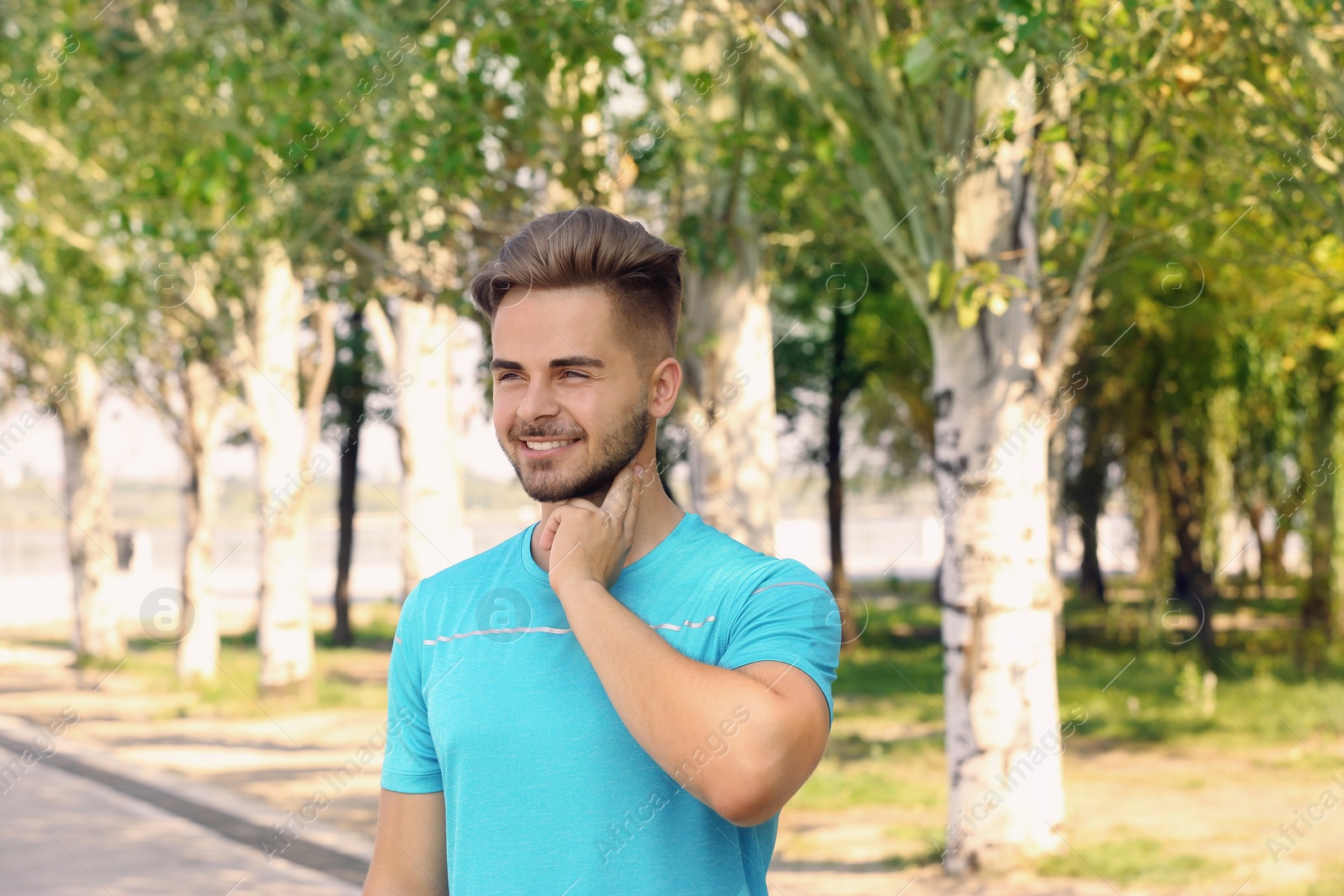 Photo of Young man checking pulse outdoors on sunny day