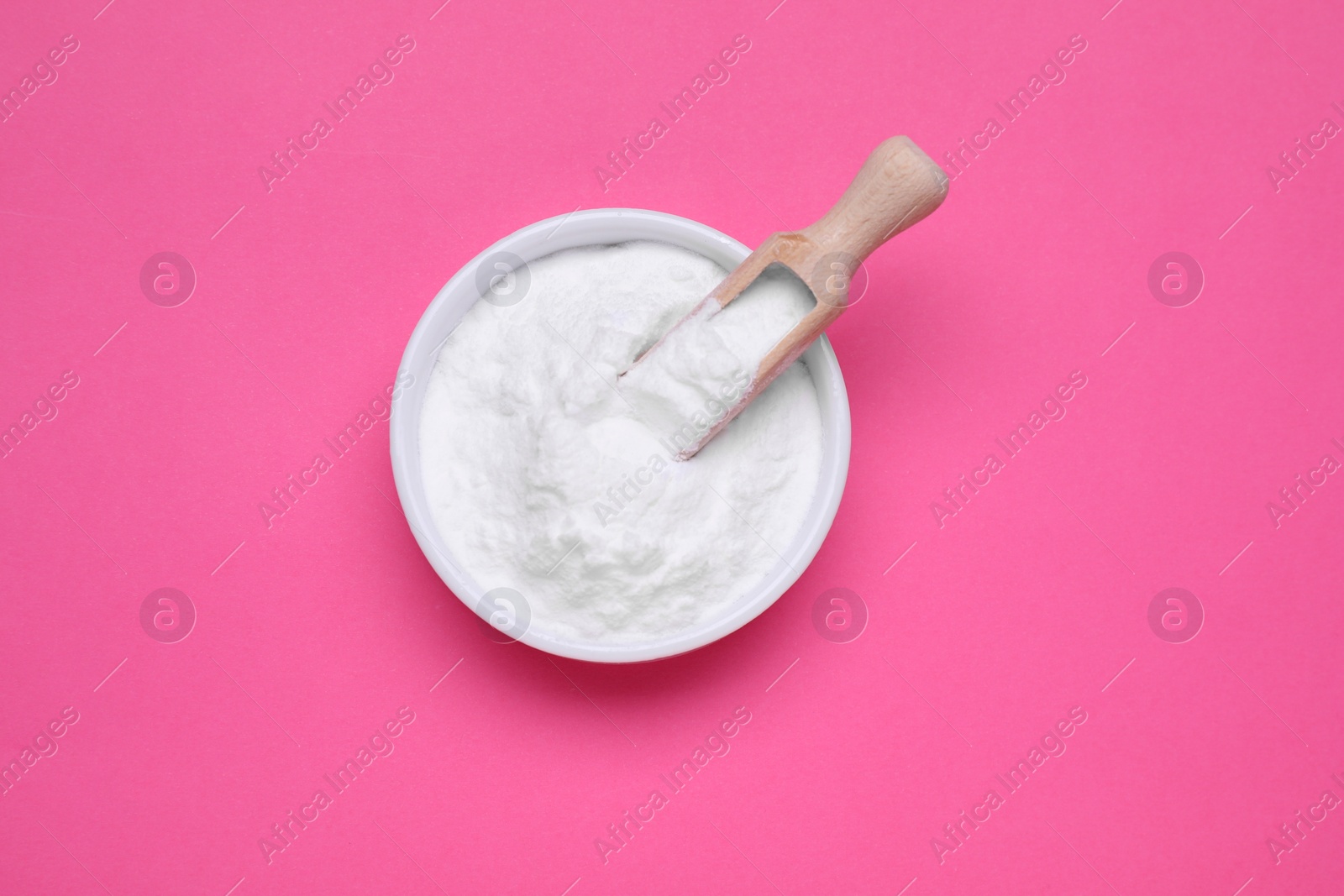 Photo of Bowl of sweet powdered fructose on pink background, top view