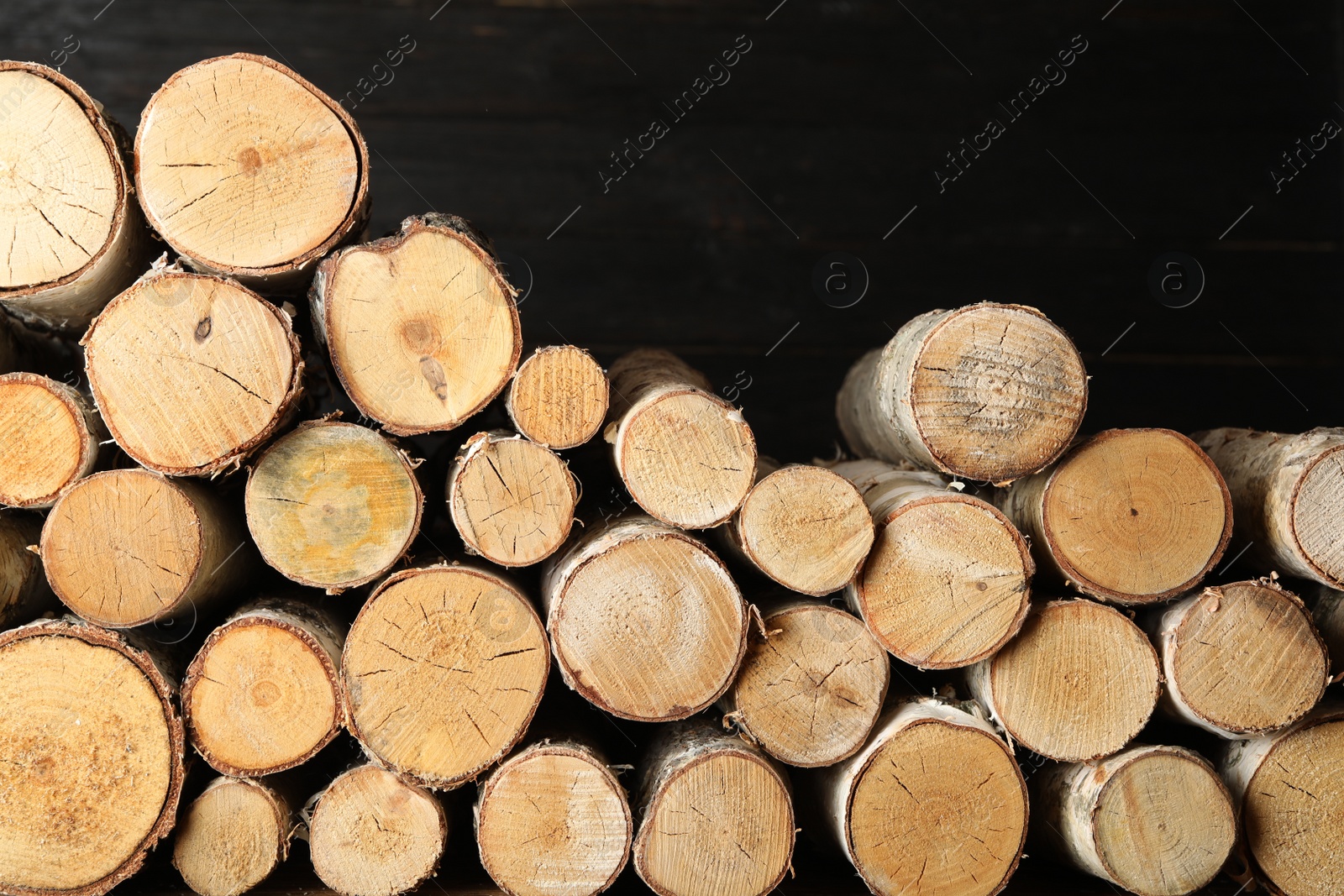 Photo of Cut firewood on black background. Heating in winter