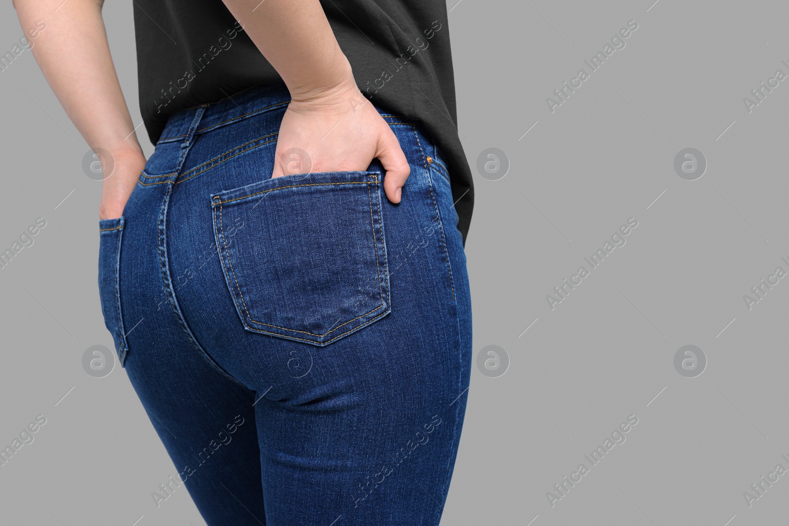 Photo of Woman in stylish jeans on grey background, closeup. Space for text