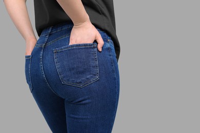 Woman in stylish jeans on grey background, closeup. Space for text